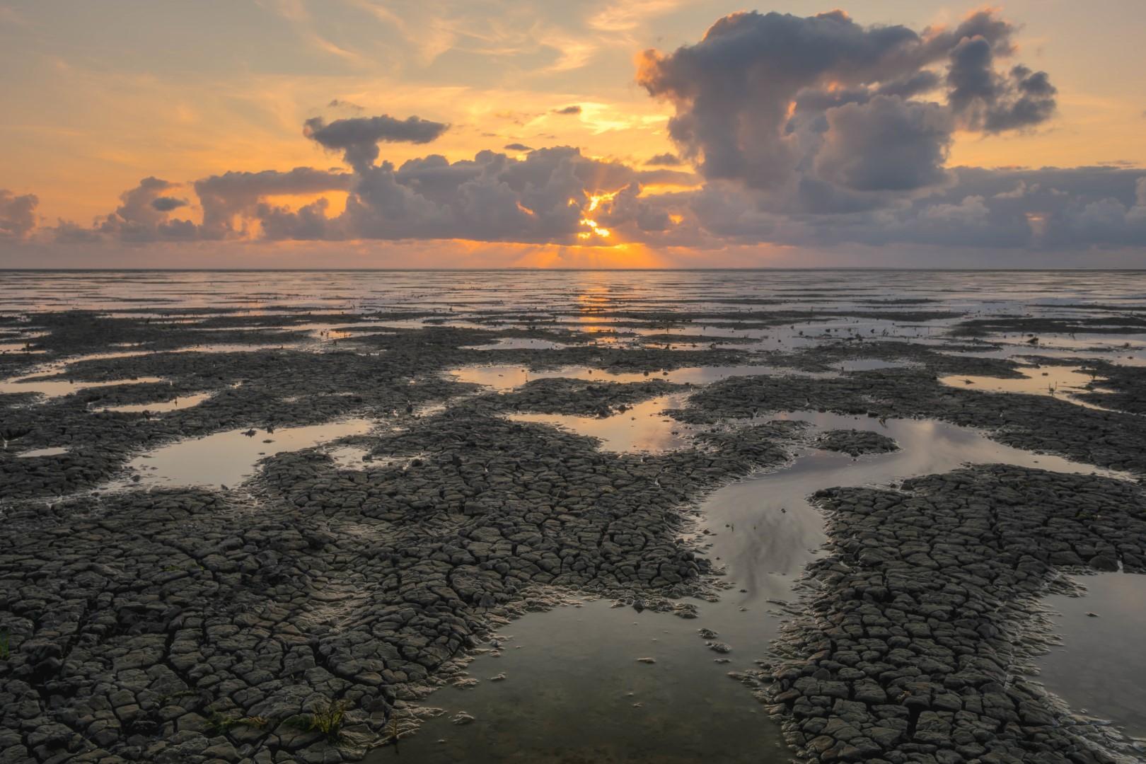 Deze foto is gemaakt op de Waddenzee nabij St. Jacobiparochie (Friesland, Nederland). De zon ging schitterend onder. Daarnaast was het ook eb, zodat er mooie structuren in de bodem zichtbaar werden. De Waddenzee is een schitterend gebied!