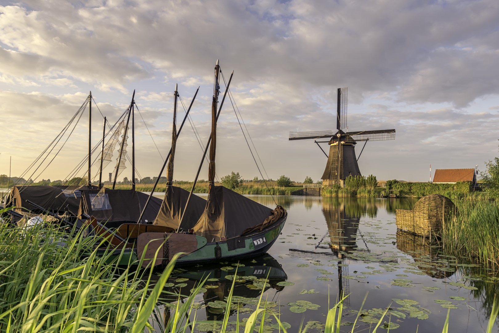 Soms sta je op een bekende, en in dit geval een veel gefotografeerde, plek! Toch was het die avond adembenemd mooi! Een bewolkte en (licht) regenachtige dag veranderde in een waar kleurspektakel. Door het vocht in de lucht knalde de kleuren extra.<br />
De lucht brak open en twee zonnenharpen waren te zien. Dit geeft voor mij een extra dimensie aan deze landschapsfoto van de Kinderdijkse molens (Zuid-Holland, Nederland).