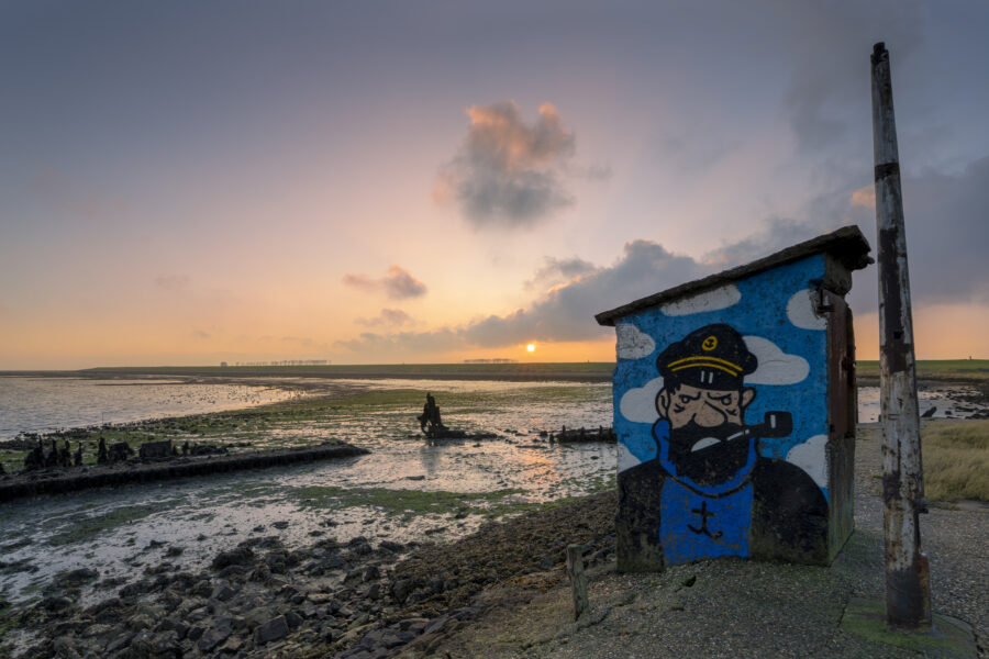 Vanmorgen onder toeziend oog van deze zeeman gefotografeerd. Het leverde een leuk contrast op met het landschap. De zon ging mooi op, maar dit werkt niet positief uit op het humeur van deze zeeman.