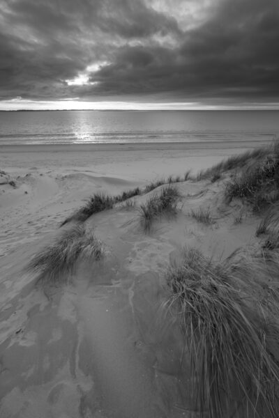 Deze foto is gemaakt aan het strand van Rockanje (Zuid-Holland, Nederland). Heel de dag was het grijs weer, maar 's middags vertoonde het wolkendek opeens gaten. En daarom maar naar deze plek gereden. Een schitterende zonsondergang was het resultaat. Deze foto voor de aardigheid omgezet in het zwart-wit
