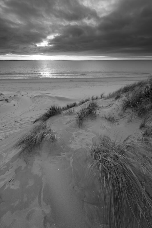 Deze foto is gemaakt aan het strand van Rockanje (Zuid-Holland, Nederland). Heel de dag was het grijs weer, maar 's middags vertoonde het wolkendek opeens gaten. En daarom maar naar deze plek gereden. Een schitterende zonsondergang was het resultaat. Deze foto voor de aardigheid omgezet in het zwart-wit