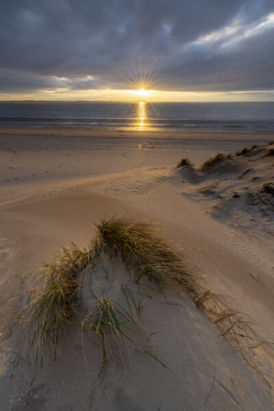 Deze foto is gemaakt aan het strand van Rockanje (Zuid-Holland, Nederland). Heel de dag was het grijs weer, maar 's middags vertoonde het wolkendek opeens gaten. En daarom maar naar deze plek gereden. Een schitterende zonsondergang, met een enorme gouden gloed viel me ten deel. Genoten aan dit strand!