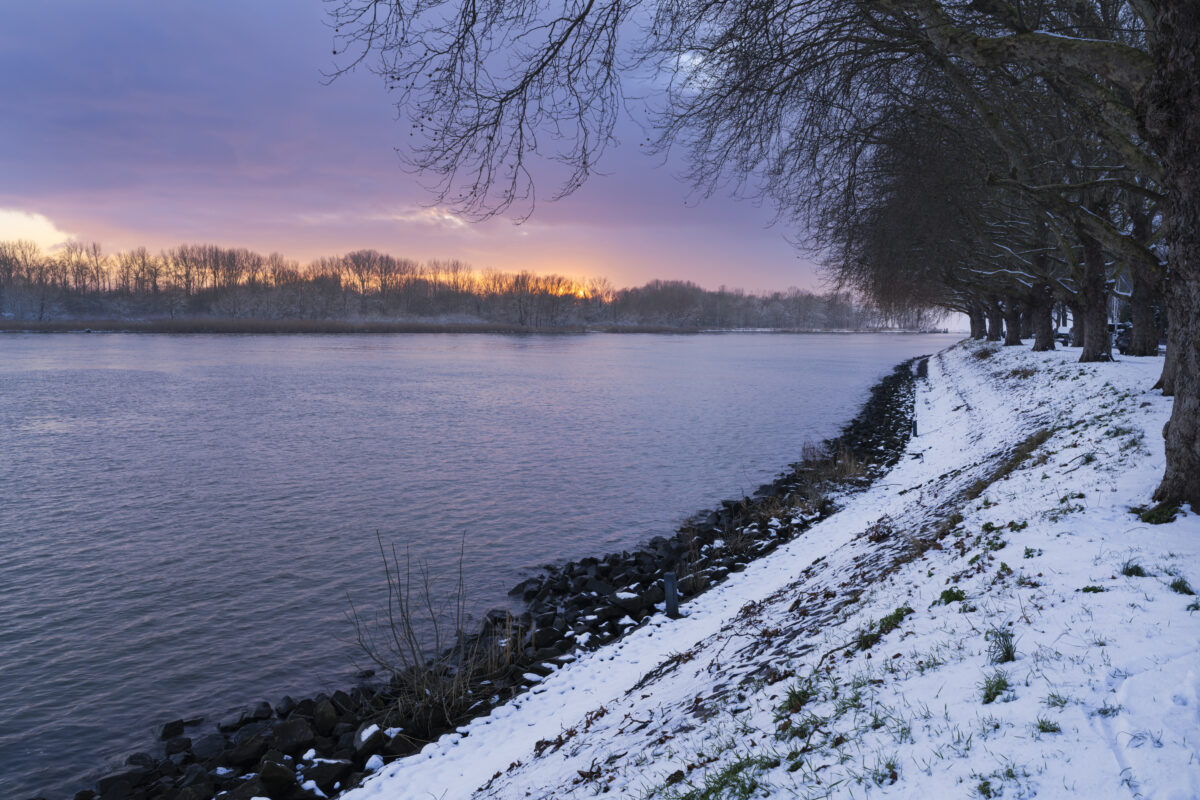 Een foto van de sneeuw in mijn woonplaats Sliedrecht (Zuid-Holland, Nederland). Langs ons dorp stroomt rivier De Merwede. Deze periode meandert de rivier in een wit sneeuwlandschap. De ondergaande zon zorgde nog voor mooie kleuren in de lucht en geeft toch noch kleur aan de foto.