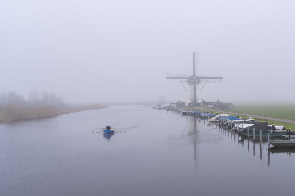 Deze foto is gemaakt bij de Kortlandse molen nabij Kortland (Zuid-Holland, Nederland). 's Middags stak een dichte mist de kop op. Toch weerhield de mist deze man niet om te gaan roeien. Al met al een leuk sfeerbeeld!