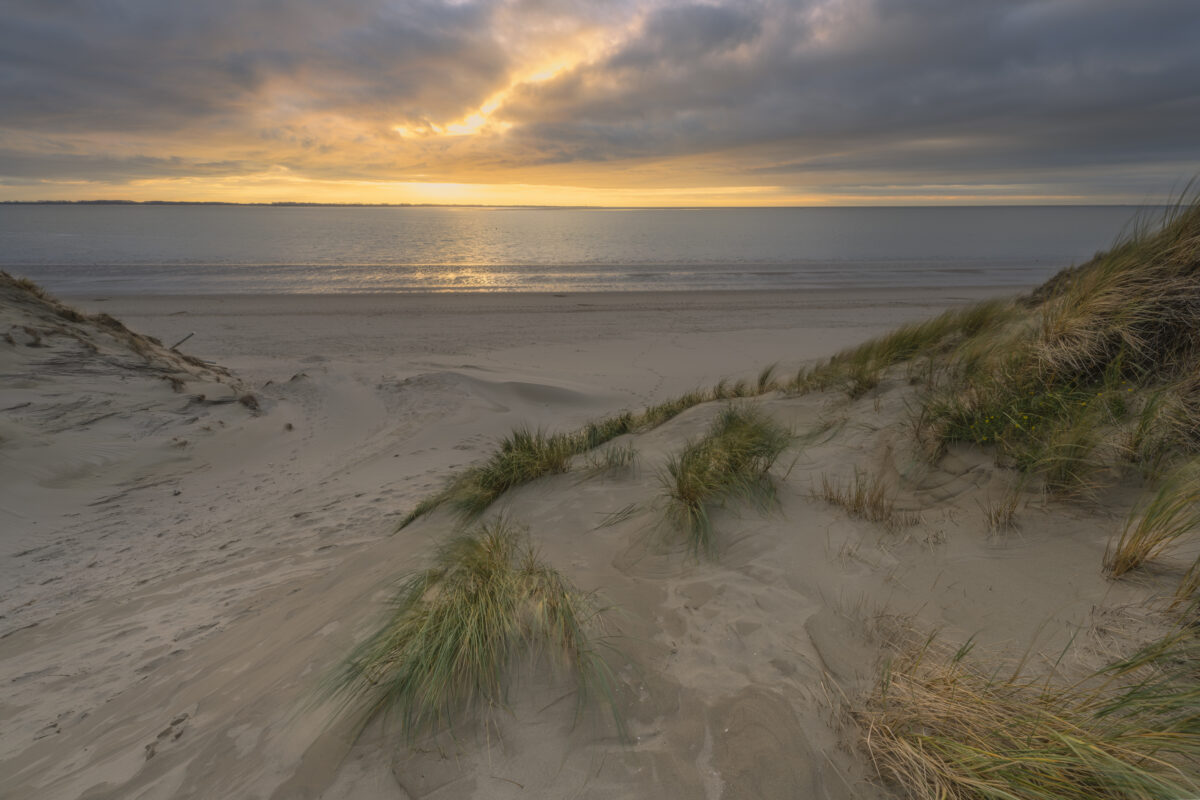 Deze foto is gemaakt aan het strand van Rockanje (Zuid-Holland, Nederland). Heel de dag was het grijs weer, maar 's middags vertoonde het wolkendek opeens gaten. En daarom maar naar deze plek gereden. Een schitterende zonsondergang was het resultaat.
