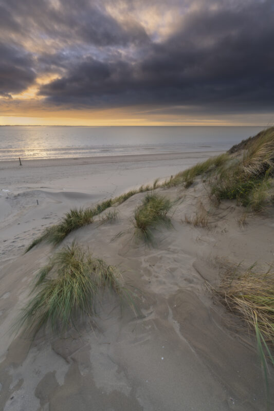 Deze foto is gemaakt aan het strand van Rockanje (Zuid-Holland, Nederland). Heel de dag was het grijs weer, maar 's middags vertoonde het wolkendek opeens gaten. En daarom maar naar deze plek gereden. Een schitterende zonsondergang was het resultaat.