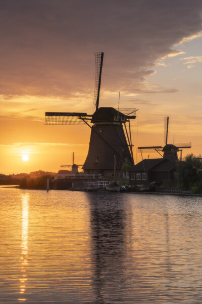 Een schitterende zonsondergang boven de molens van UNESCO Werelderfgoed de Kinderdijkse Molens te Kinderdijk (Zuid-Holland, Nederland). Deze dag werd een hitterecord bereik en was de lucht strakblauw. Maar 's avonds werd bewolking opgegeven. Ik ben naar dit bekende plekje gereden om heerlijk te genieten van de omstandigheden het het fotograferen van dit landschap.