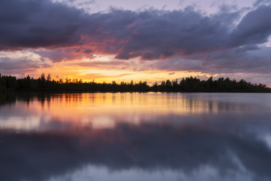 Een schitterende zonsondergang boven Nationaal Park De Biesbosch. Achter mij dreigde alweer een volgende onweersbui, maar voor mij ging de zon schitterend onder. Het zette de dreigende wolken in brand. Door het vele vocht in de lucht waren de kleuren nog intenser. Heerlijk om deze kleuren weerspiegelt te zien in het water. Een heerlijk moment om deze landschapsfoto te kunnen maken.