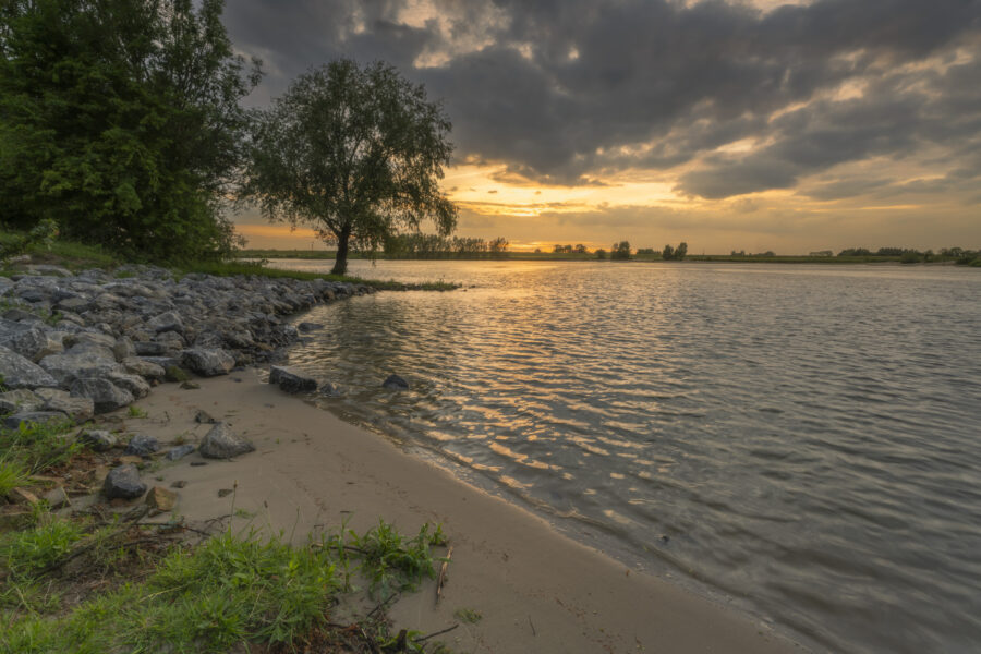 Deze foto is gemaakt bij Middelwaard nabij Vianen (Utrecht, Nederland). De zon ging in een gouden gloed onder. Kabbelend water zorgde voor een innerlijke rust. Een mooie plek voor landschapsfotografie.