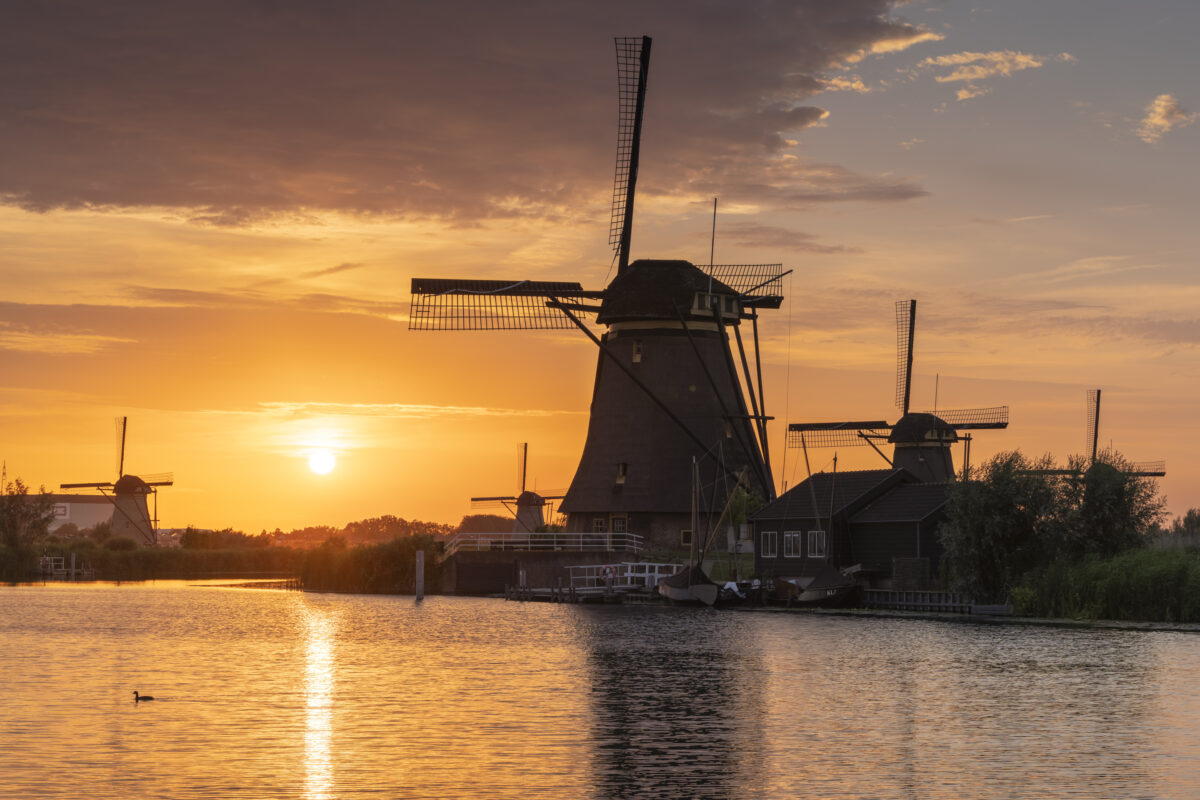 Een schitterende zonsondergang boven de molens van UNESCO Werelderfgoed de Kinderdijkse Molens te Kinderdijk (Zuid-Holland, Nederland). Deze dag werd een hitterecord bereik en was de lucht strakblauw. Maar 's avonds werd bewolking opgegeven. Ik ben naar dit bekende plekje gereden om heerlijk te genieten van de omstandigheden het het fotograferen van dit landschap.